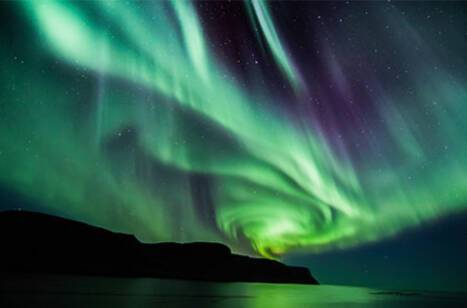 The northern lights in the night sky above water