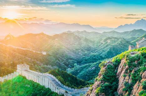 A panoramic view of the sun rising over the Great Wall of China