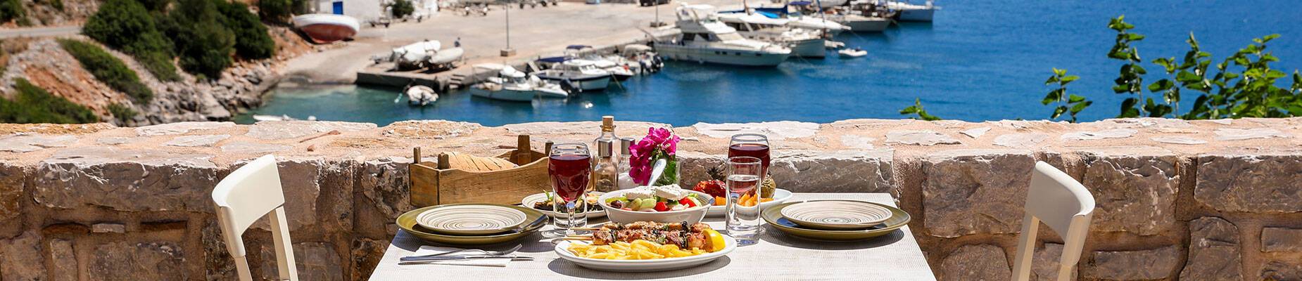 A table for two with chicken souvlaki, French fries, Greek salad and Greek wine