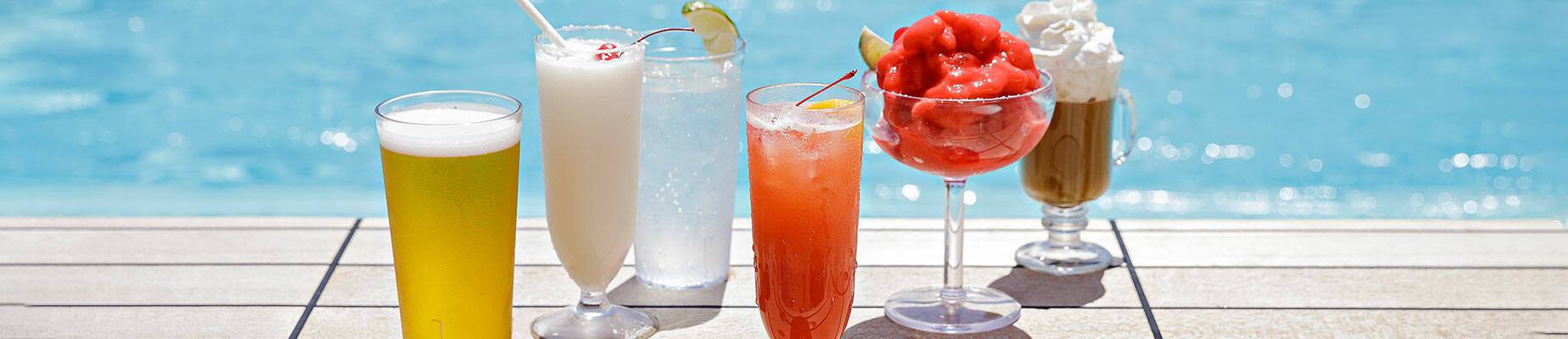 A row of drinks on the side of a swimming pool