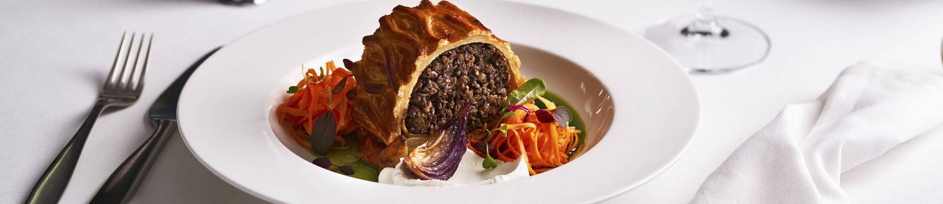 A closeup image of a meal and glass of wine in P&O Cruises' Epicurean restaurant