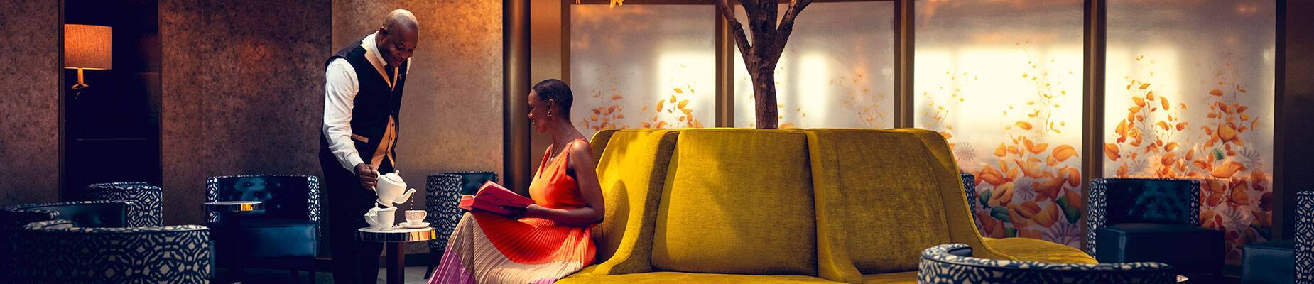A waiter serving a guest tea in the Grills Lounge on Queen Anne