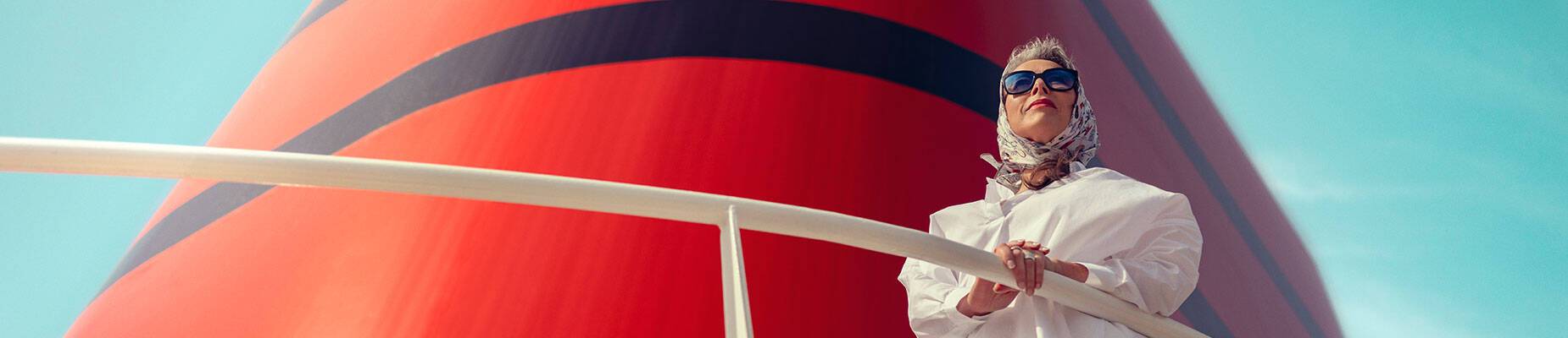 A woman standing in front of the funnel on a Cunard cruise ship