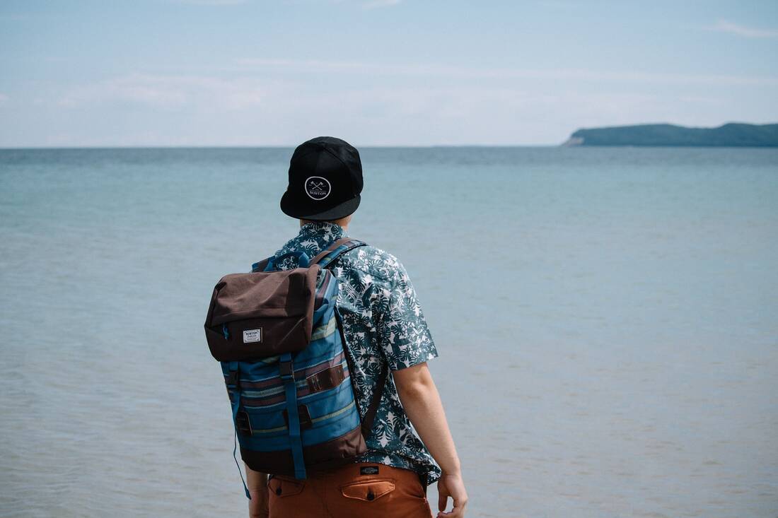 Man on beach carrying a rucksack