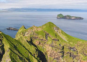 Woman looking out over the cliffs in Heimaey