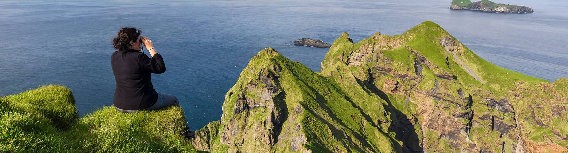 Woman looking out over the cliffs in Heimaey